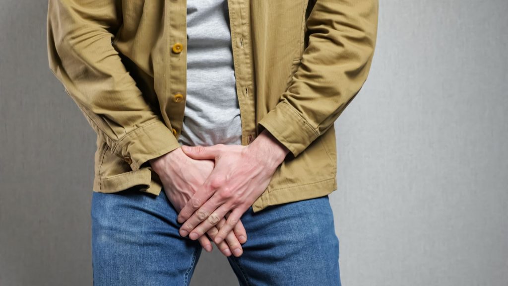 Close-up of a man holding his groin, representing urinary incontinence often experienced after prostate surgery.