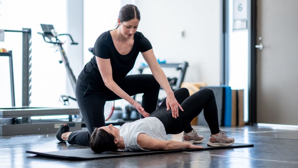 Female physiotherapist guiding a patient through pelvic floor strengthening exercises to treat urinary incontinence.