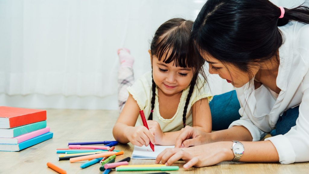 A young child drawing with a parent, strengthening fine motor skills and hand–eye coordination.