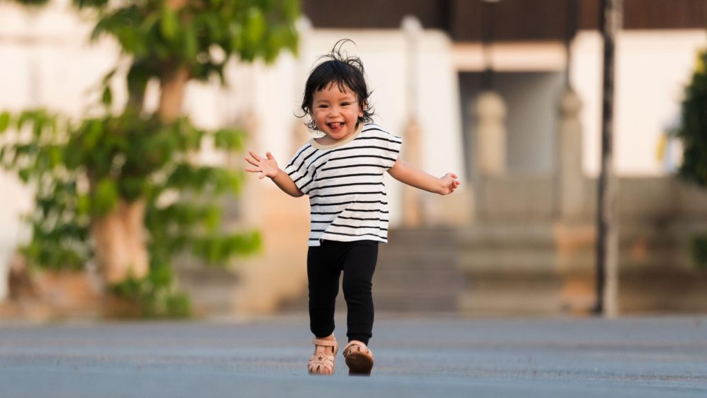 A happy toddler running outdoors, showing confidence and coordination as part of normal motor development.