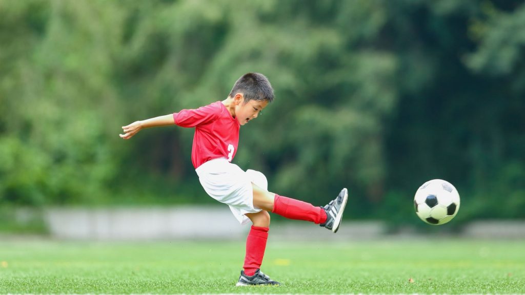 Young boy kicking a football, showing that children with intoeing can still play sports actively.