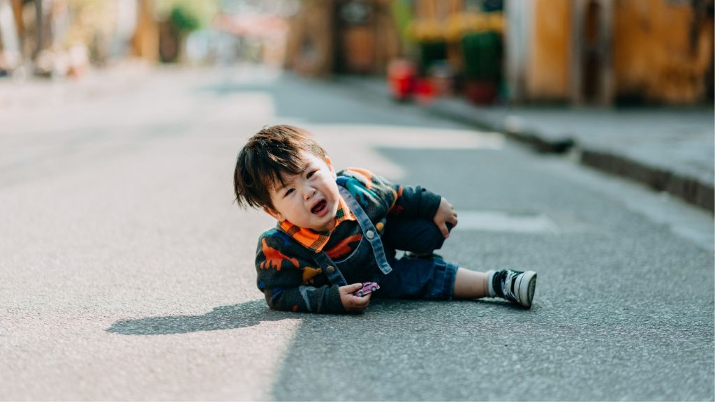 Toddler crying after tripping outdoors, a common sign parents notice in children with intoeing.
