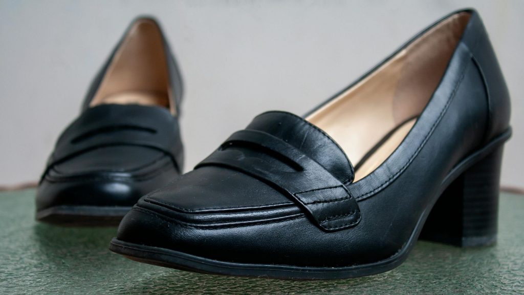 Woman testing different ballet flats on a wooden floor, showing common footwear linked to women’s foot pain.