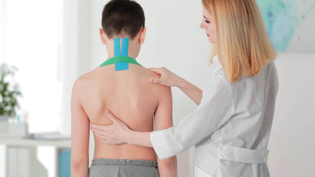 Child with physiotherapy tape on back during scoliosis in children treatment