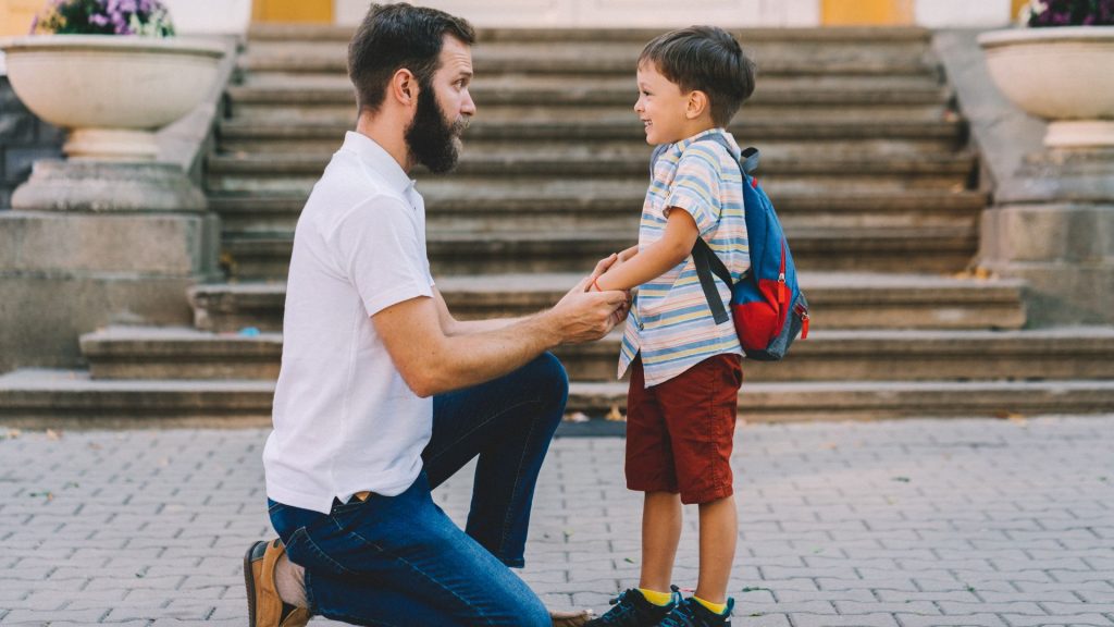 Parent supporting child with schoolbag, discussing posture and scoliosis in children