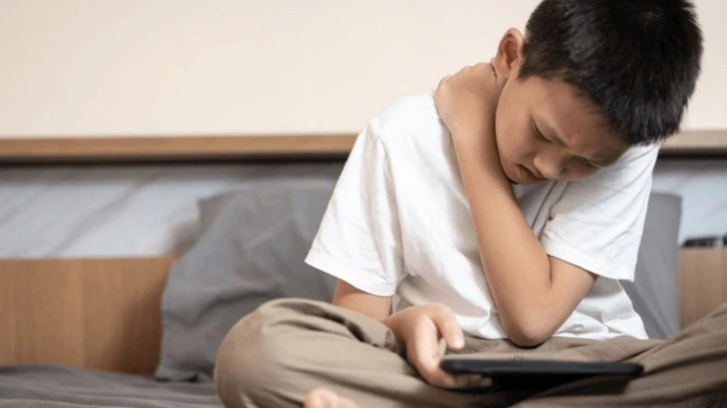 Child with poor posture using tablet, showing early signs of scoliosis in children