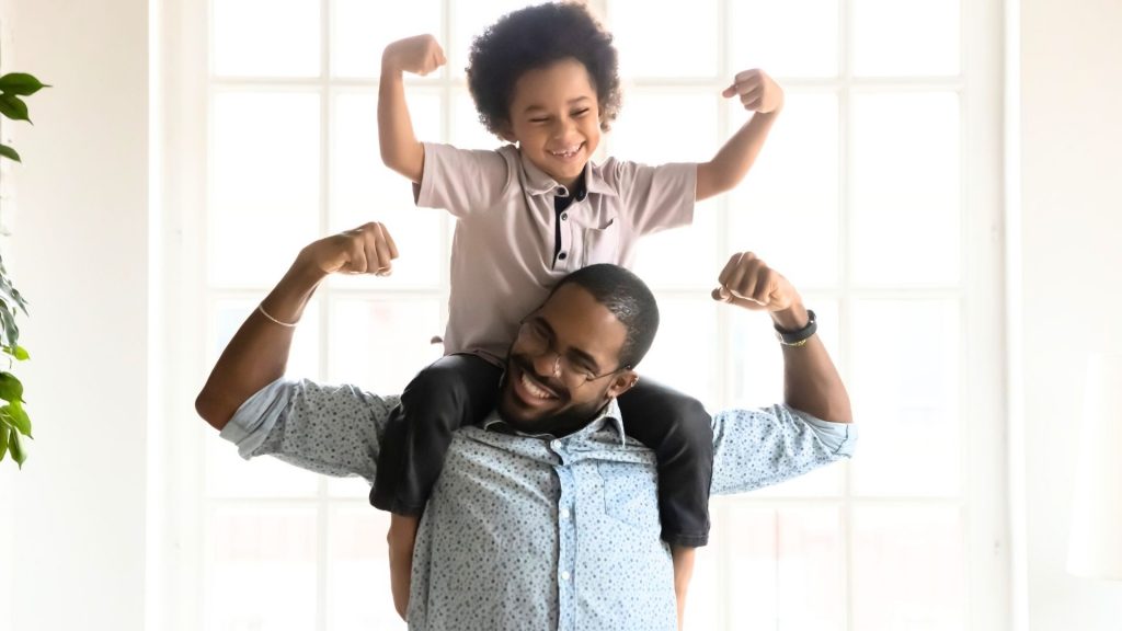 Child showing strength and confidence with father’s support after scoliosis in children treatment