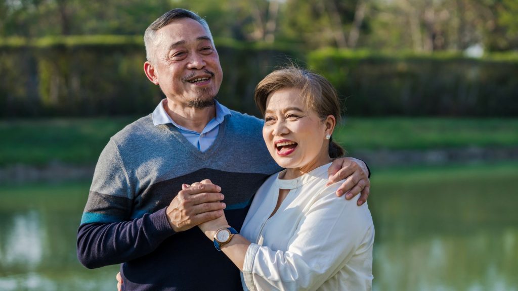 Smiling elderly couple outdoors, showing improved quality of life after successful urinary incontinence treatment.