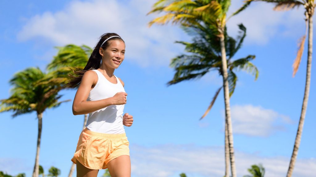Smiling woman jogging outdoors, representing confidence and freedom after urinary incontinence treatment.
